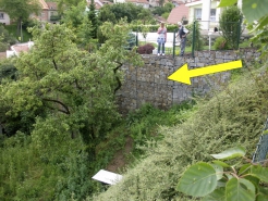 Obr. 16: Svahovým pohybem narušená gabionová zeď (šipka)